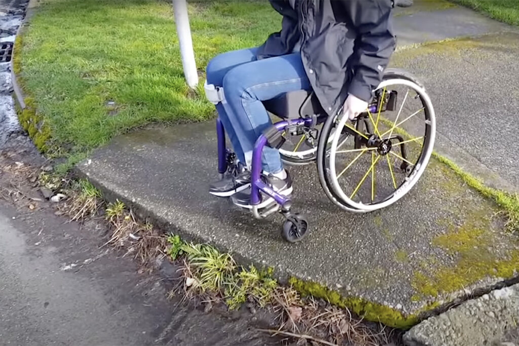 person in wheelchair at sidewalk curb